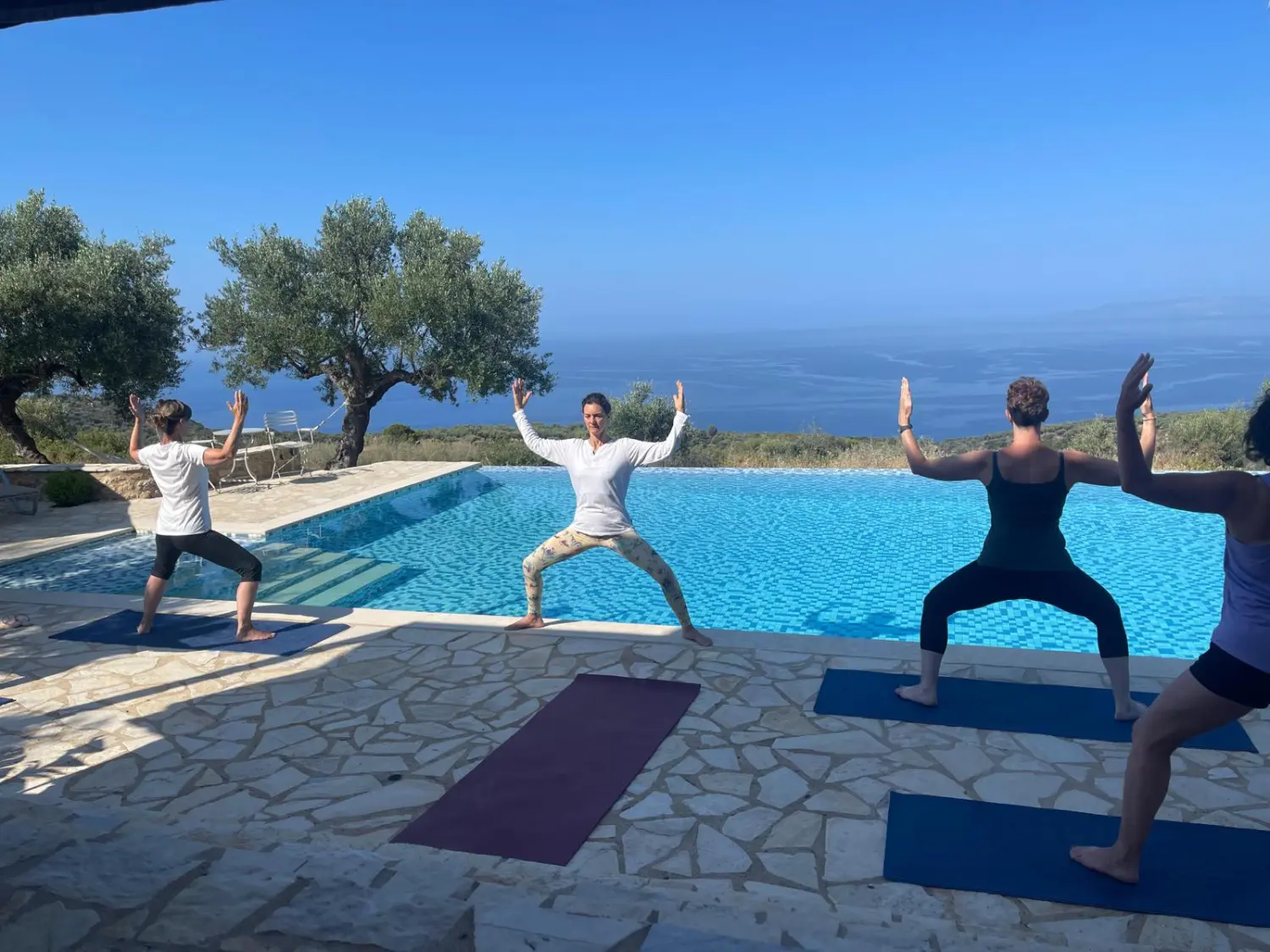 Praxis Lebenswege – Frauen praktizieren Yoga in der Nähe eines Pools in einer natürlichen Umgebung